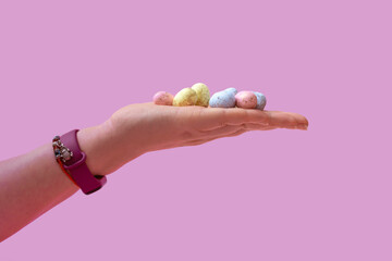 Natural colored quail eggs in a female hand on a pink background. Banner. Closeup