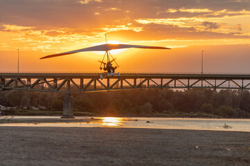 A motor glider at sunset over the bridge