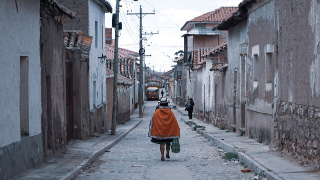 Tarabuco, Bolivia, March 2020. A local women walking in the middle of village. She wears local and traditional red pancho.