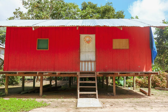 Amazon forest village, Colombia, 11.2019. A typical wooden house painted red on Amazon Forest, local little village. Wooden local forest house with little stairs.