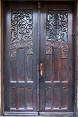brown antique wooden double door with glass and forged decor