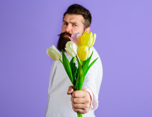 Bearded man with flowers. Handsome male with Bouquet tulips for birthday. Valentines or Womens Day.