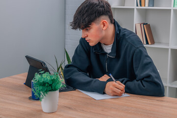 teen boy at home studying with computer or tablet