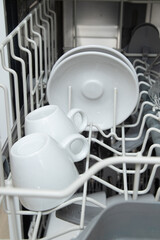 White dishes in the dishwasher. Homework with dishwasher concept