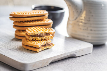 Sweet sandvich cookies. Biscuits with cocoa cream filling on white cutting board.