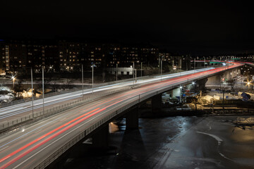 Fototapeta na wymiar Cars and trucks driving at night over a bridge on a higly trafficated road in the middle of a city over a river