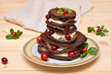 Obraz na płótnie Canvas a stack of chocolate pancakes with cranberries on a plate close-up