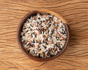 Raw assorted rice in a bowl over wooden table