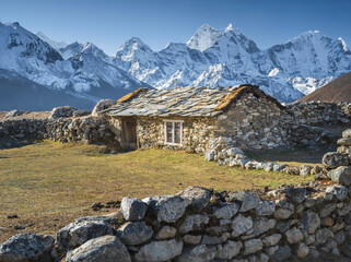 view to rural farmer house behind stone fence with view to snow peaks of Himalaya in Nepal