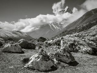 view to stones and vally Khumbu with clouds on the peaks in monochrome style in Nepal