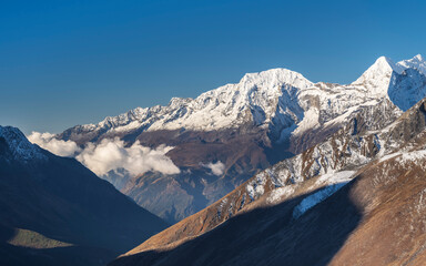 view to mountain valley with hills and snow peaks under blue sky in Nepal