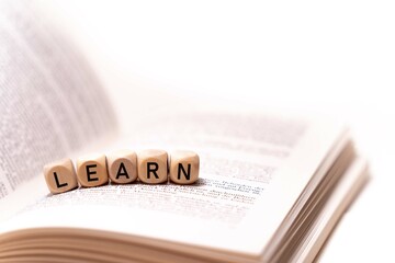 the word LEARN spelled on an open book with wooden letters, concept picture with white background