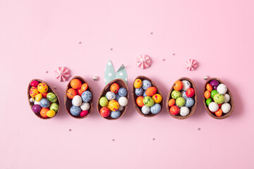 Chocolate easter eggs and decor flat lay for kids easter hunt egg concept on pink background....