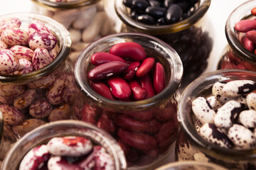 .Different types of beans, background. Lots of white, red, black and colorful beans, background. Wooden spoon with white beans..