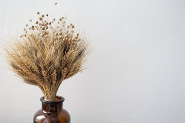 A simple brown vase with a bouquet of wheat. Home decor. Place for your text.