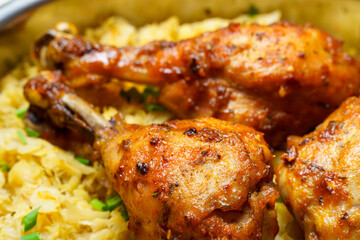 fried chicken legs in a frying pan with stewed chopped cabbage, cooked food in a rustic style as a background