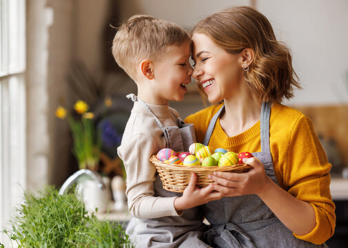 Sweet family portrait of young mother and little son with wicker basket full of painted Easter eggs