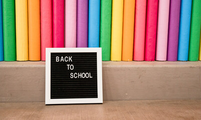 Oversized rainbow colored pencils with small letter board sign that reads 