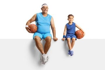 Mature man in jersey holding a basketball and sitting on a blank panel with a little boy
