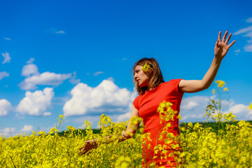 Young pretty woman in a colored dress on Lightning cheerful yellow background blooming rapeseed...