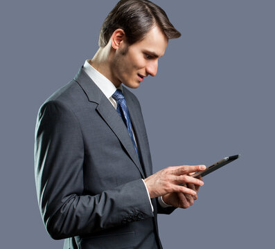 businessman using tablet computer in front of grey background