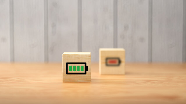 cubes with battery symbols, symbolizing charging on wooden background - Powered by Adobe