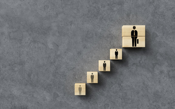 cubes forming a stair with people symbols symbolizing step by step progress on concrete background