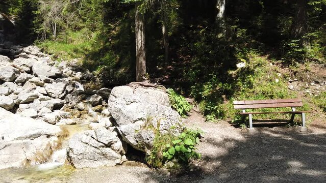 Sonniger Fr&uuml;hling Tag im Wald.  Lass uns entspannen auf einer Sitzbank im Wald, neben ein felsiger Gebirgsbach und frische gr&uuml;ne Bl&auml;tter. Wandern und meditieren in Bayern Alpen, Deutschland, Europe.
