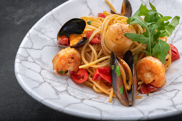 Spaghetti with seafood, scallop, shrimp, mussels on a dark background with space for text