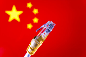 Internet in China concept. Ethernet cable connector and blurred Chinese flag on the background....
