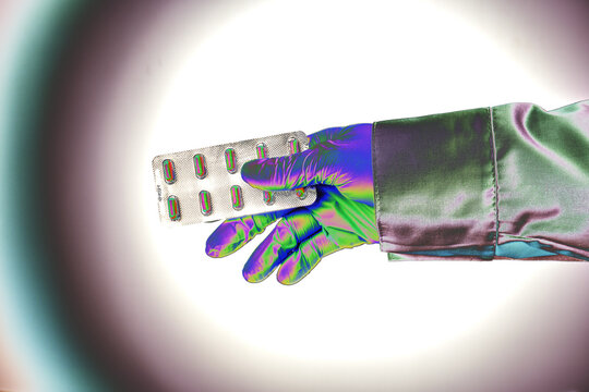 A hand gives a pill blister - psychedelics style photo. Shine hole effect. Doctor hand offers painkiller remedy. Hope of success treatment. Flare tunnel to immortality. Energy of medical drugs.