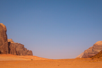 Fototapeta na wymiar Two tiny hikers in the vast Wadi Rum desert, Jordan
