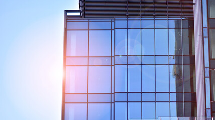 Fragments of building in business district of modern city. High-rise office building in downtown. Modern architecture of typical concrete, glass and steel.