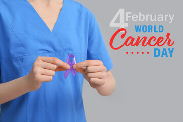 Female nurse with awareness ribbon on grey background. World Cancer Day