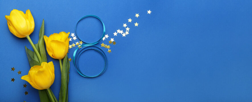 Figure 8 made of ribbon and tulip flowers for International Women's Day celebration on blue background with space for text