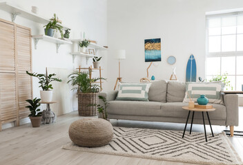 Stylish grey sofa with houseplants in modern interior of living room