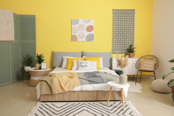 Stylish interior of modern bedroom with yellow wall