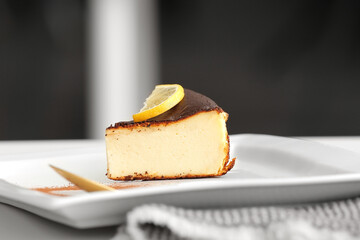 Plate with slice of tasty Basque burnt cheesecake on table, closeup