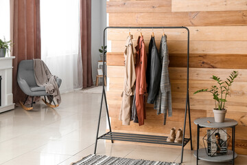 Obraz na płótnie Canvas Rack with female outwear clothes and shoes near wooden wall