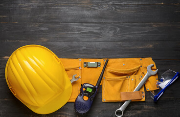 Safety equipment with radio transmitter and builder's tools on dark wooden background
