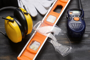 Safety equipment with builder's level and radio transmitter on dark wooden background