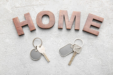 Word HOME and keys with stylish keychains on light background
