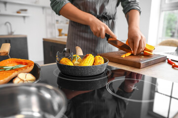 Frying pan with tasty corn on stove in kitchen, closeup