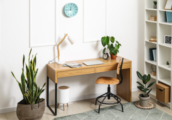 Interior of stylish living room with modern workplace, shelving unit and houseplants