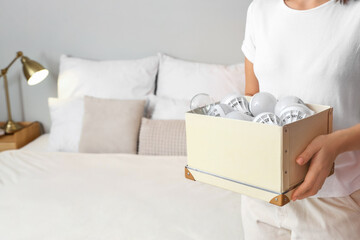 Woman holding box with light bulbs in bedroom, closeup