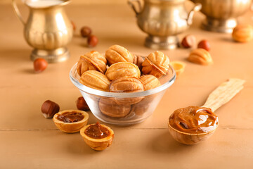 Bowl of tasty walnut shaped cookies with boiled condensed milk on  wooden background
