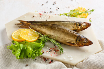 Board with smoked herring fishes on white background