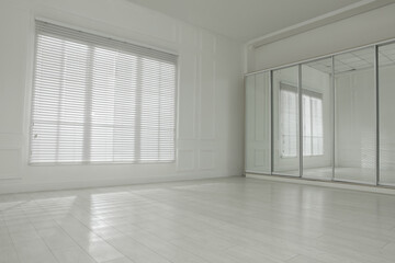 Empty room with white walls, large window and wooden floor