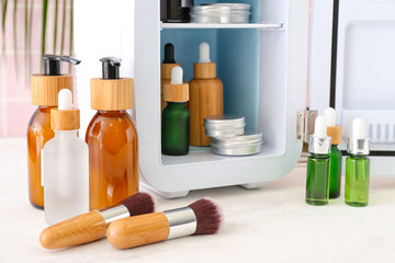 Small refrigerator with cosmetic products on table, closeup