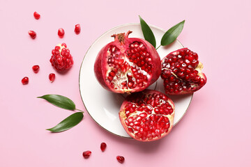 Plate with ripe delicious pomegranate on pink background